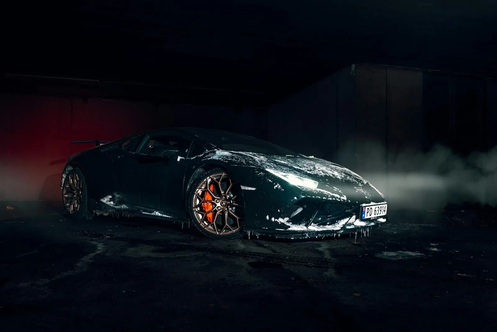 Tmavé Lamborghini se zbytky pěny v šeru garáže